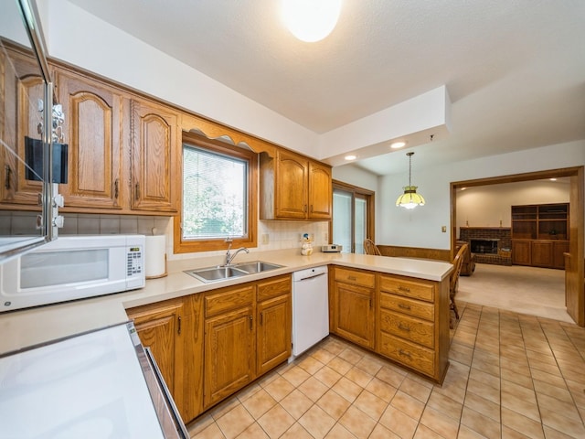 kitchen with white appliances, a sink, a peninsula, brown cabinets, and light tile patterned floors