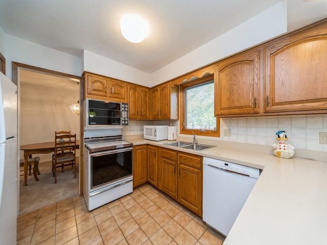 kitchen featuring white appliances, brown cabinetry, light countertops, and decorative backsplash