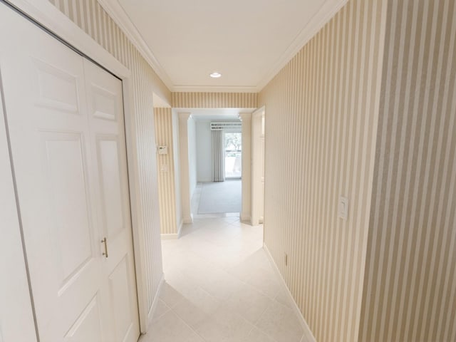 corridor featuring crown molding, baseboards, light tile patterned flooring, and wallpapered walls