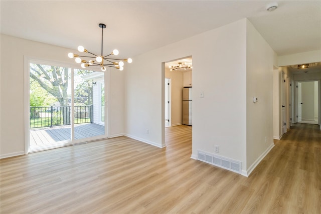 spare room with a chandelier, light wood-type flooring, a smoke detector, and baseboards