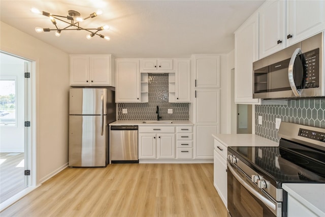 kitchen with appliances with stainless steel finishes, a chandelier, decorative backsplash, a sink, and light wood-type flooring