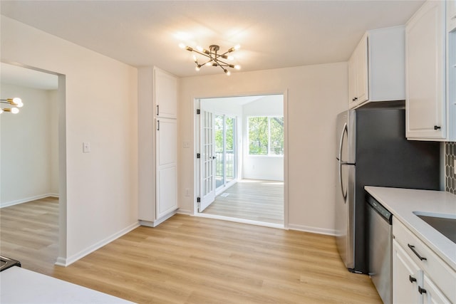 kitchen featuring a chandelier, stainless steel dishwasher, light wood finished floors, and white cabinets