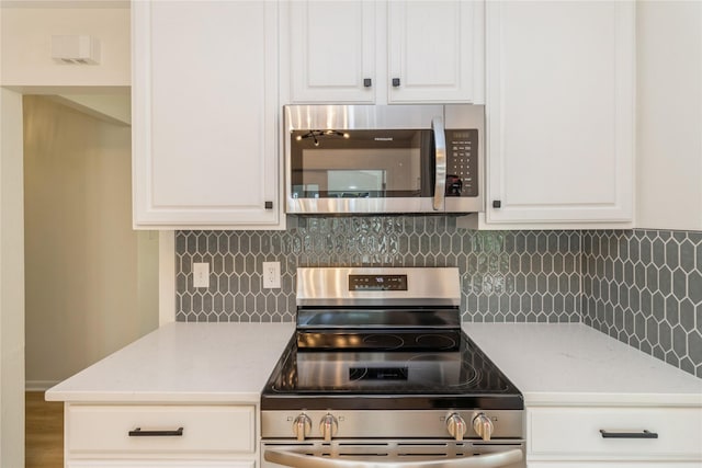 kitchen featuring stainless steel appliances, light countertops, white cabinets, and backsplash