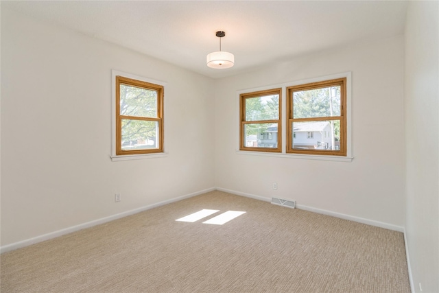 empty room featuring healthy amount of natural light, carpet flooring, and baseboards