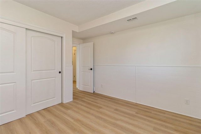 unfurnished bedroom featuring light wood finished floors and a closet