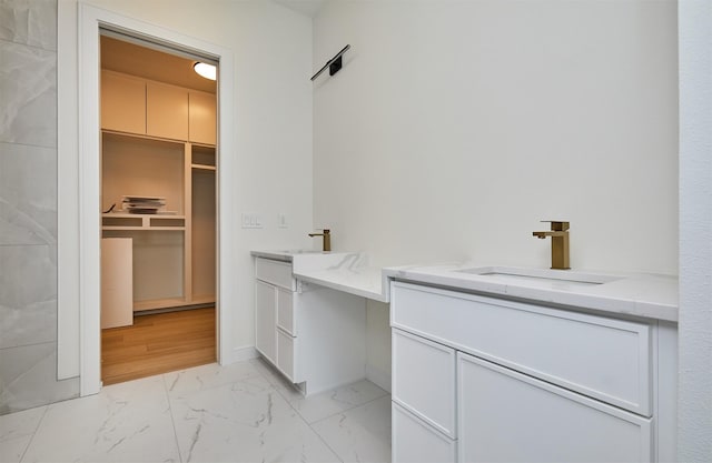 4727 Hillsdale Dr, Urbandale, IA 50322 - bathroom featuring marble finish flooring, two vanities, a walk in closet, and baseboards