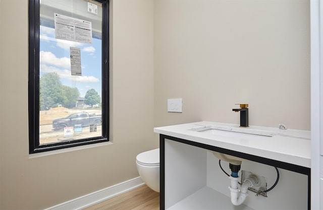 4727 Hillsdale Dr, Urbandale, IA 50322 - bathroom featuring toilet, wood finished floors, baseboards, and a sink