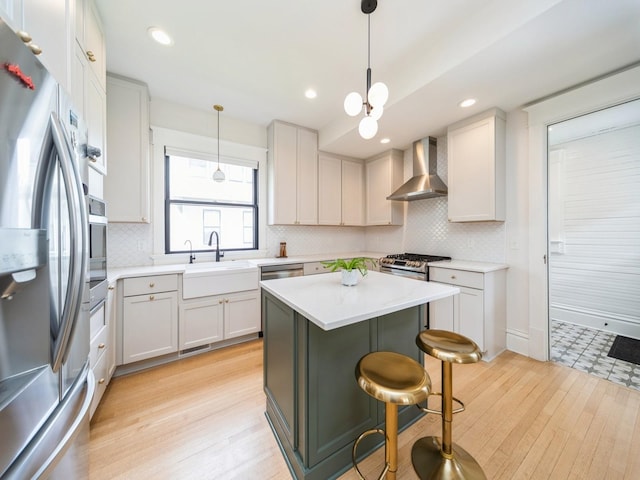 kitchen with stainless steel appliances, wall chimney exhaust hood, a sink, light countertops, and tasteful backsplash