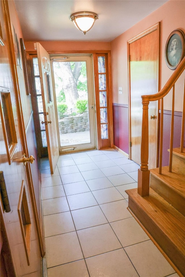 doorway featuring wainscoting, stairs, and light tile patterned flooring