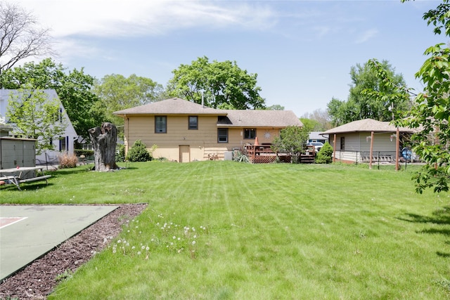 rear view of house featuring a wooden deck and a lawn