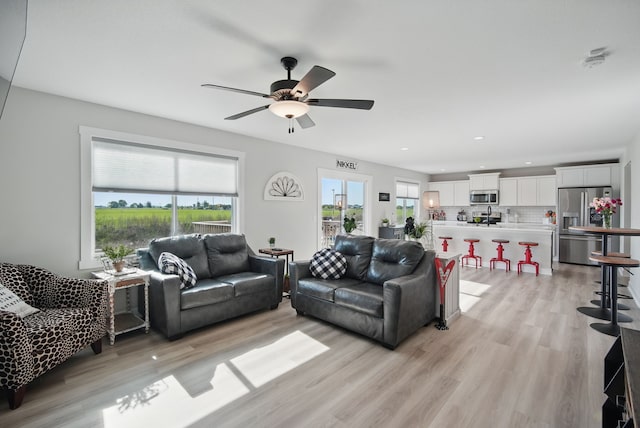 living area featuring light wood finished floors, ceiling fan, and recessed lighting