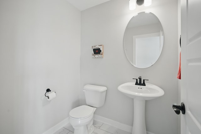 bathroom with toilet, baseboards, and a sink