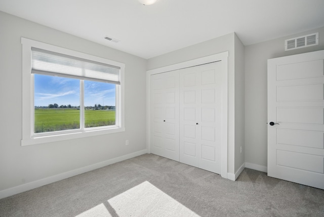 unfurnished bedroom featuring light colored carpet, a closet, and baseboards