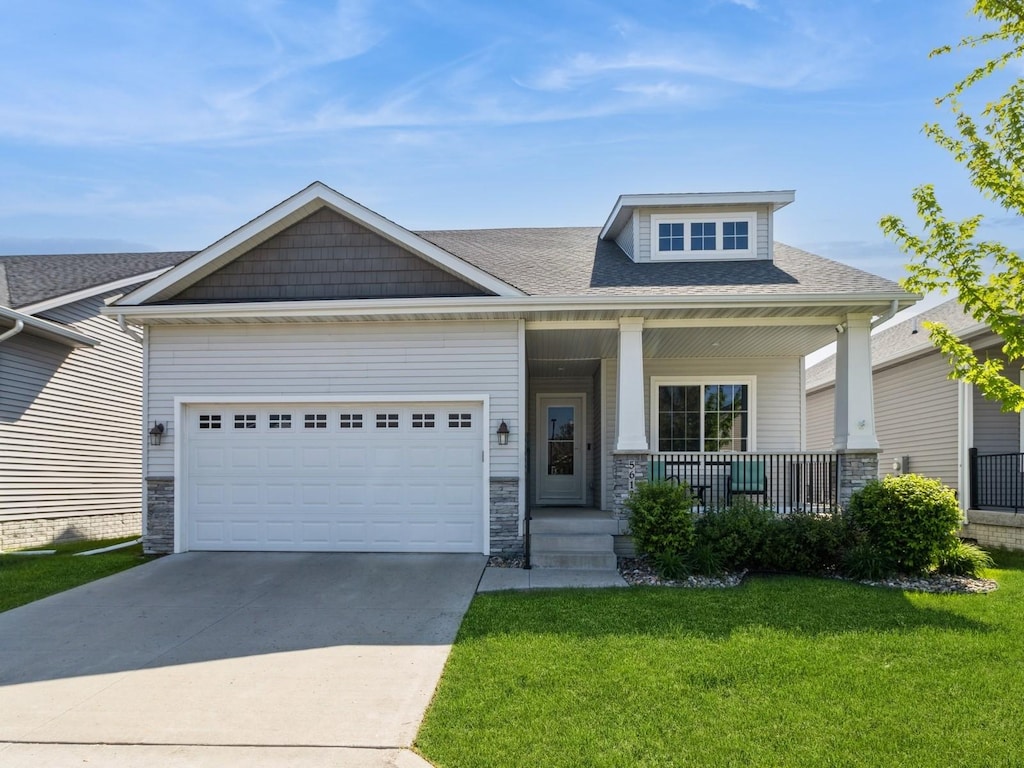 5617 Woodreed Ln, Johnston, IA 50131 - craftsman inspired home featuring covered porch, concrete driveway, a front lawn, a garage, and a shingled roof