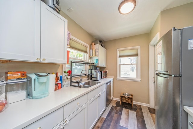1523 Allison Ave, Des Moines, IA 50314 - kitchen with stainless steel appliances, a sink, white cabinetry, light countertops, and dark wood-type flooring