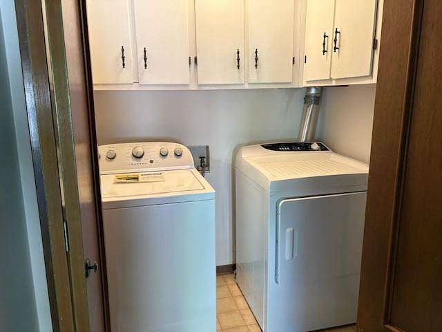 clothes washing area with washing machine and clothes dryer, cabinet space, and light tile patterned flooring