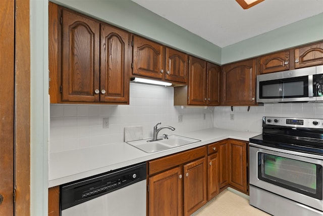 kitchen featuring appliances with stainless steel finishes, a sink, light countertops, and decorative backsplash
