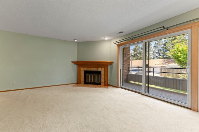 unfurnished living room with carpet floors, baseboards, a tile fireplace, and a textured ceiling