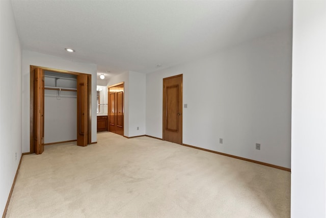 unfurnished bedroom with light carpet, baseboards, recessed lighting, a closet, and ensuite bath