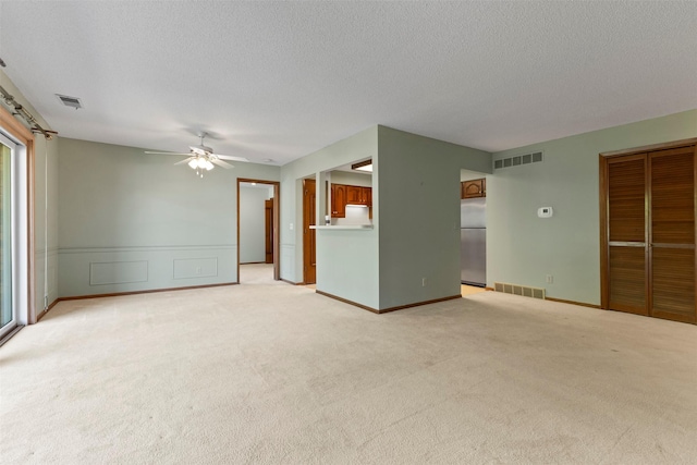 unfurnished living room featuring light colored carpet, ceiling fan, and a textured ceiling