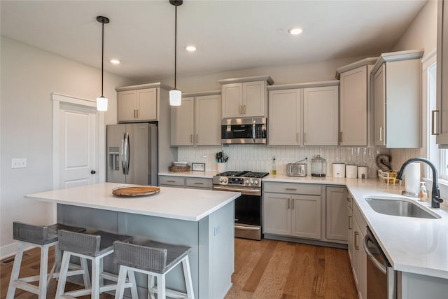 2920 Oak St, Norwalk, IA 50211 - kitchen with appliances with stainless steel finishes, a sink, gray cabinets, a breakfast bar area, and backsplash