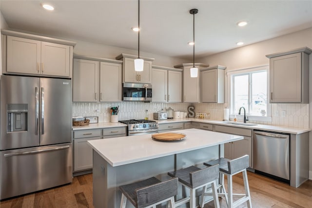 2920 Oak St, Norwalk, IA 50211 - kitchen with stainless steel appliances, a sink, gray cabinetry, backsplash, and wood finished floors