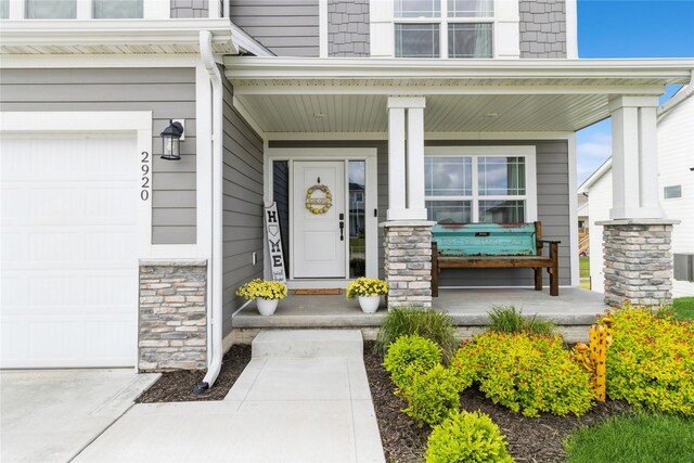 2920 Oak St, Norwalk, IA 50211 - entrance to property featuring covered porch, stone siding, and a garage