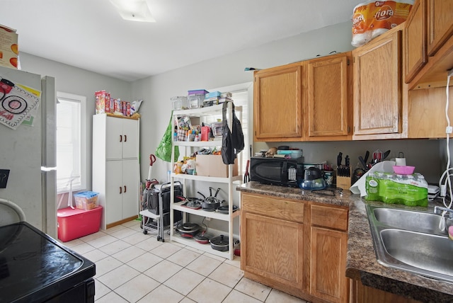 2057 Maple St, Des Moines, IA 50317 - kitchen with black microwave, a sink, light tile patterned floors, and dark countertops