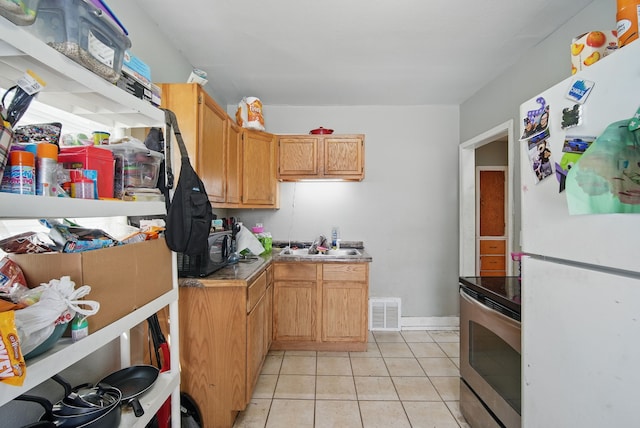 2057 Maple St, Des Moines, IA 50317 - kitchen featuring freestanding refrigerator, stainless steel electric range, light tile patterned flooring, and a sink