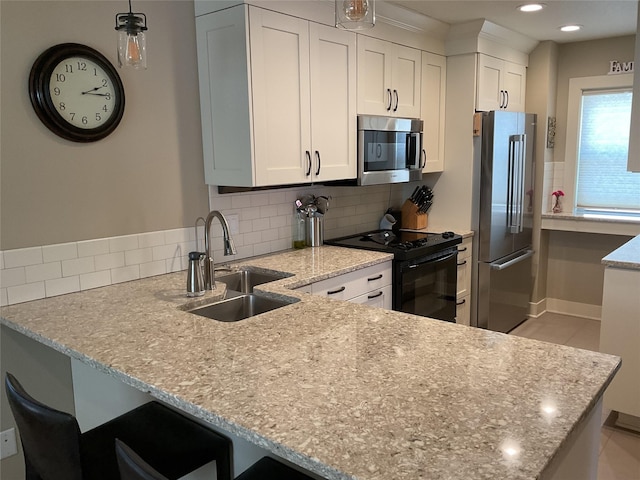kitchen with stainless steel appliances, a peninsula, a sink, backsplash, and white cabinets