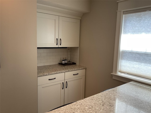 kitchen with decorative backsplash, plenty of natural light, and white cabinetry