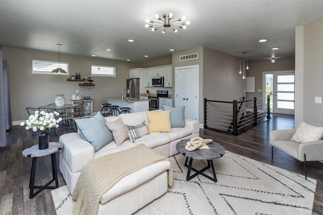 living area with wood finished floors, healthy amount of natural light, recessed lighting, a chandelier, and baseboards
