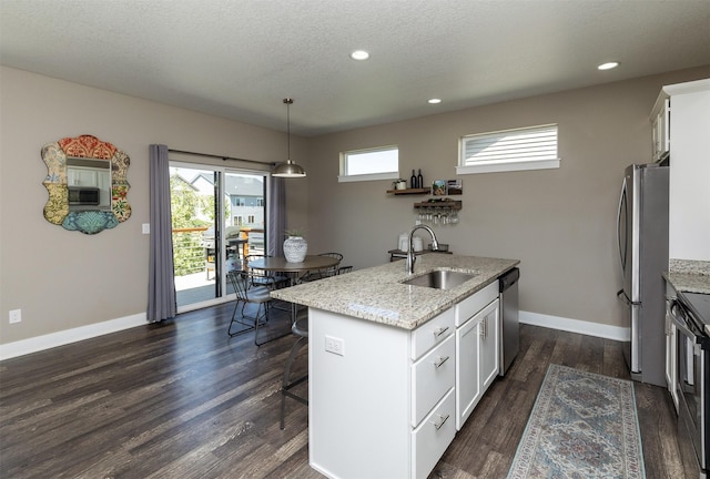 kitchen featuring a sink, appliances with stainless steel finishes, a kitchen breakfast bar, light stone countertops, and white cabinets