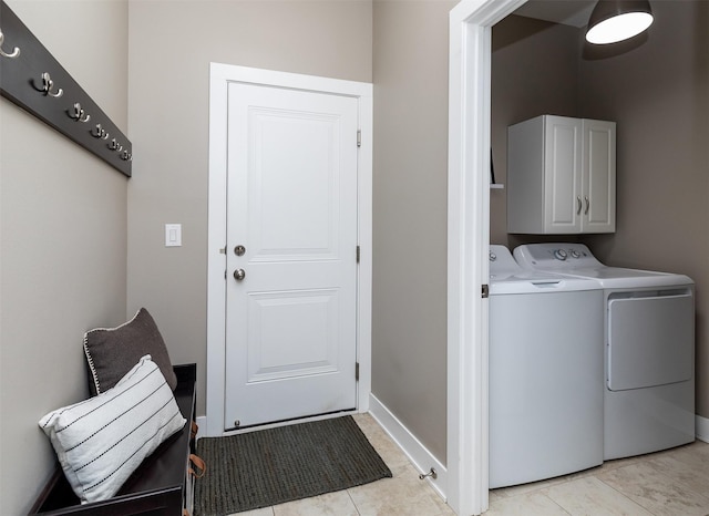 washroom featuring washer and clothes dryer, cabinet space, baseboards, and light tile patterned floors