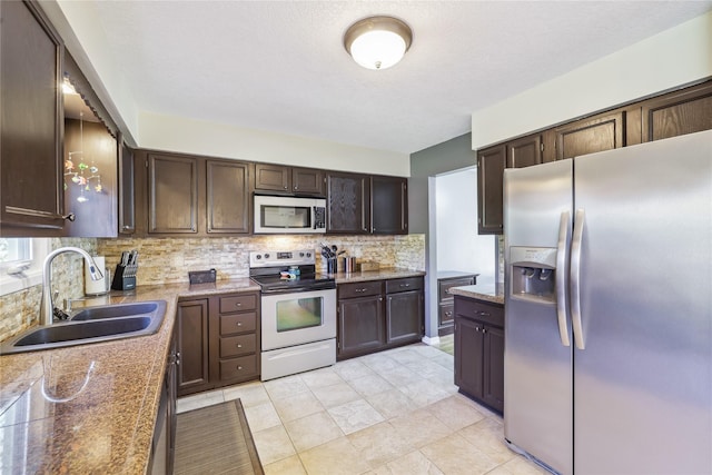 4727 80th Pl, Urbandale, IA 50322 - kitchen featuring appliances with stainless steel finishes, backsplash, dark brown cabinets, and light stone countertops