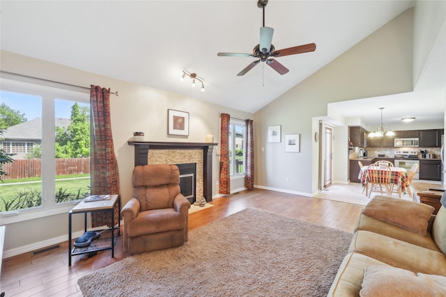 4727 80th Pl, Urbandale, IA 50322 - living area featuring light wood-style floors, a fireplace, a ceiling fan, a chandelier, and high vaulted ceiling