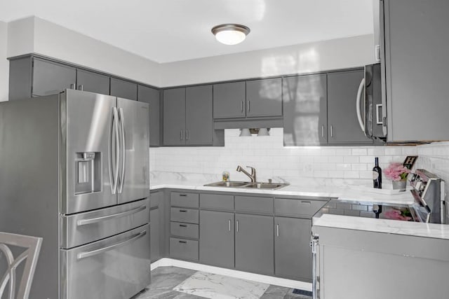 518 Maxwelton Dr, Des Moines, IA 50315 - kitchen featuring appliances with stainless steel finishes, gray cabinets, a sink, light marble finish floors, and decorative backsplash