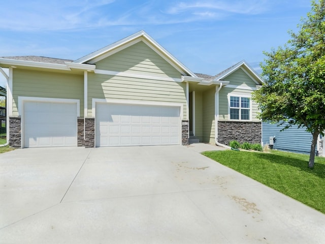 view of front of house with stone siding, an attached garage, concrete driveway, and a front yard
