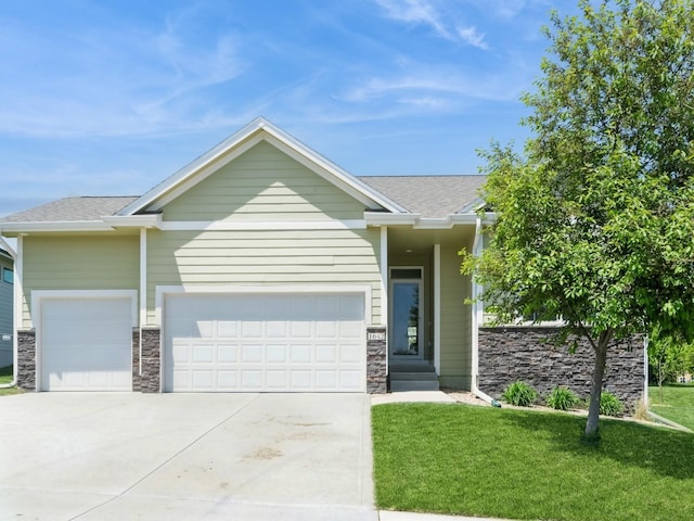 view of front facade with an attached garage, a front lawn, driveway, and stone siding
