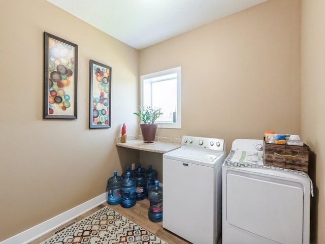 washroom with washer and clothes dryer, baseboards, and wood finished floors