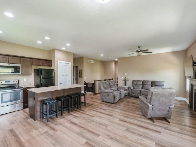 living area featuring ceiling fan, light wood-style flooring, recessed lighting, and baseboards