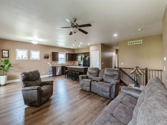 living room featuring a ceiling fan, light wood-type flooring, baseboards, and recessed lighting