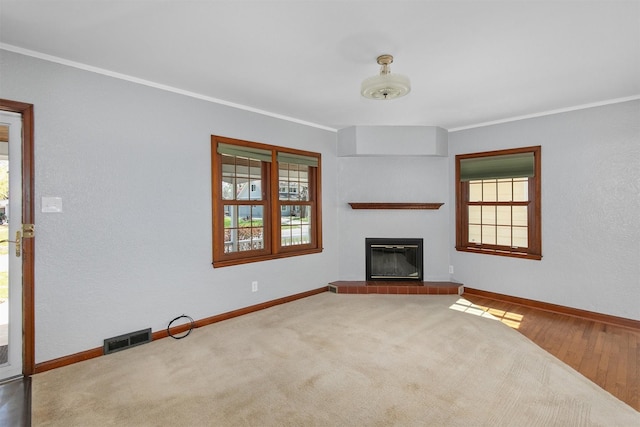 2400 39th St, Des Moines, IA 50310 - unfurnished living room featuring crown molding, a tiled fireplace, baseboards, and wood finished floors