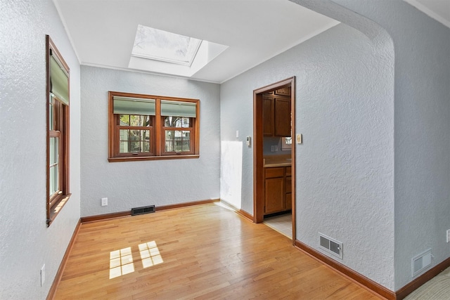 2400 39th St, Des Moines, IA 50310 - unfurnished room featuring a skylight, a textured wall, wood finished floors, and healthy amount of natural light
