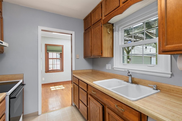 2400 39th St, Des Moines, IA 50310 - kitchen featuring a sink, range with electric cooktop, light countertops, baseboards, and brown cabinets