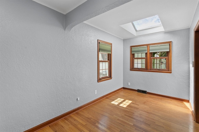 2400 39th St, Des Moines, IA 50310 - empty room featuring a skylight, wood finished floors, a textured wall, ornamental molding, and baseboards