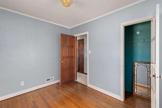 2400 39th St, Des Moines, IA 50310 - unfurnished bedroom with baseboards, wood finished floors, crown molding, and a closet