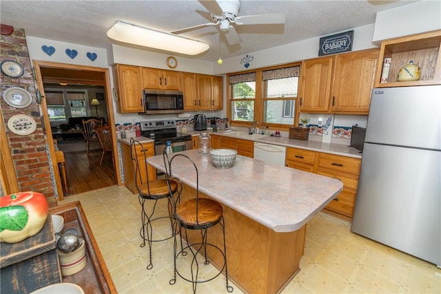 kitchen with stainless steel appliances, light flooring, a ceiling fan, light countertops, and a sink