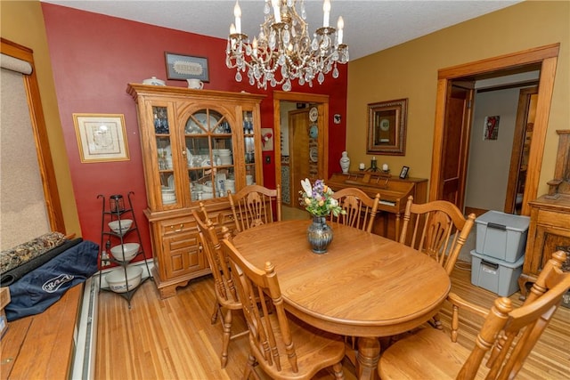 dining area featuring light wood finished floors, a chandelier, and a textured ceiling