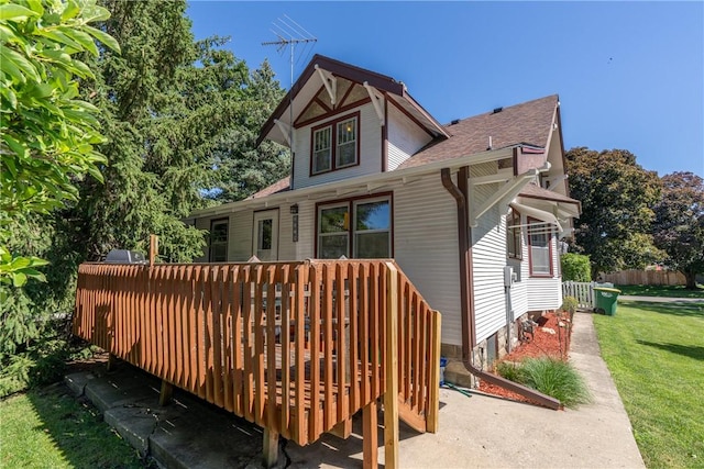 back of house featuring a wooden deck and roof with shingles